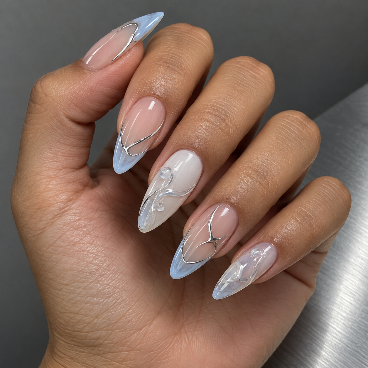 Almond nails with ice-blue glass tips and sculptural silver nail art